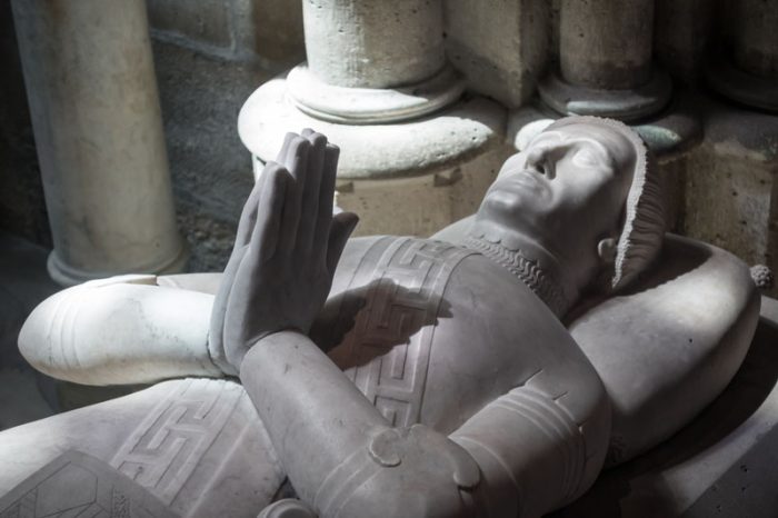 Statue en marbre d'un roi allongé, faisant un signe de prière avec ses mains