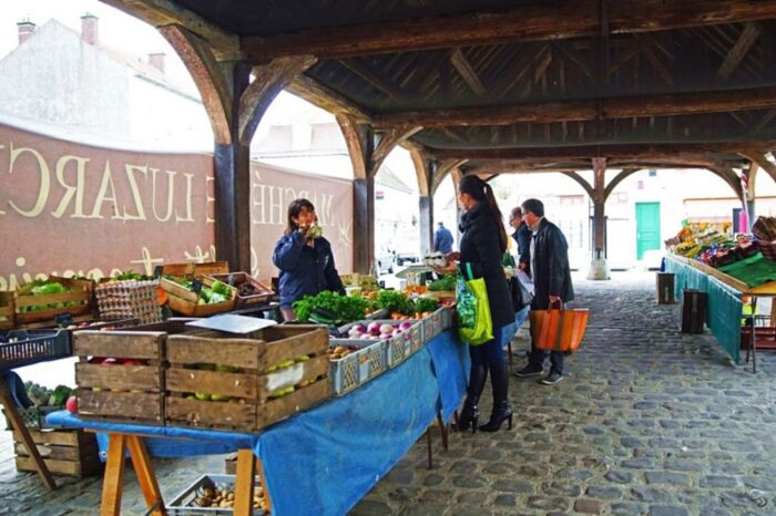 Photo du marché de Luzarches avec des marchands et des clients sous une halle