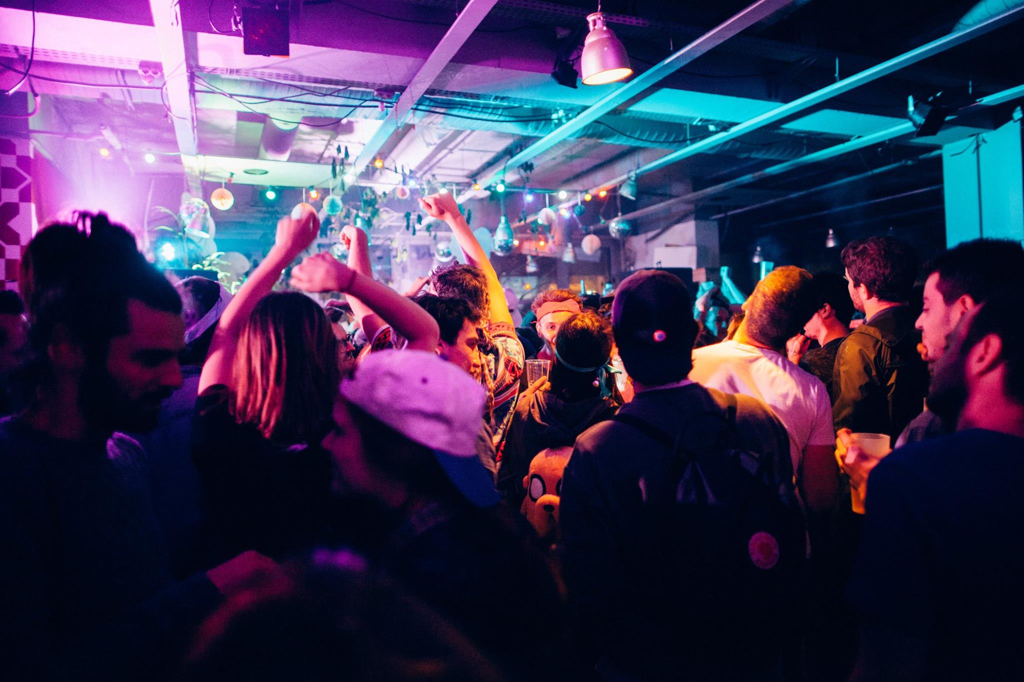 Photo d'une soirée en intérieur à l'éclair. On voit des gens danser sous les lumières néons