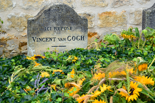 Photo de la tombe de Vincent van Gogh recouverte de végétation et de tournesols